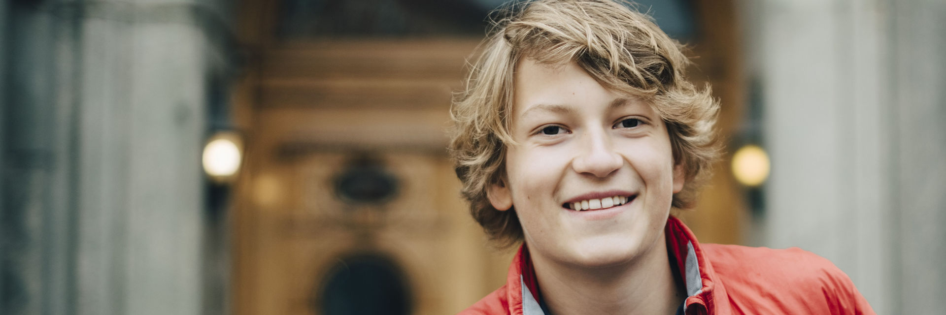 Jugend entscheidet – Lächelnder Junge vor einem Gebäude in der Stadt